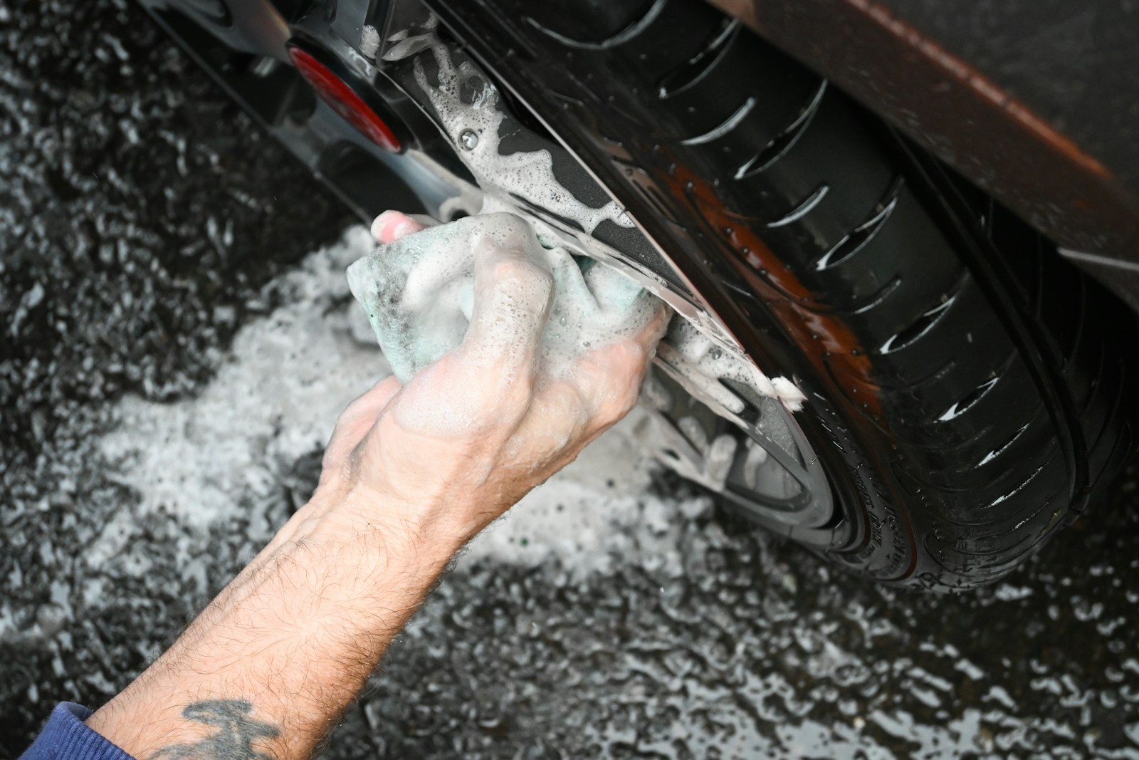 a man washing a car tire with a rag